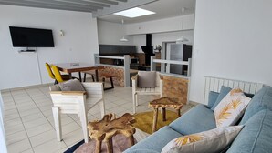Una sala moderna con un sofá, una mesa de comedor y una cocina al fondo.