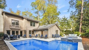 A two-story building with a swimming pool, outdoor seating, and a covered area.