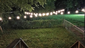 A grassy outdoor area with string lights and wooden structures.