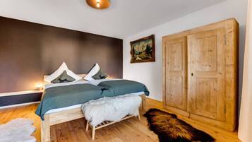 Une chambre à coucher avec un lit, une armoire en bois, un tableau et un tapis en fourrure.