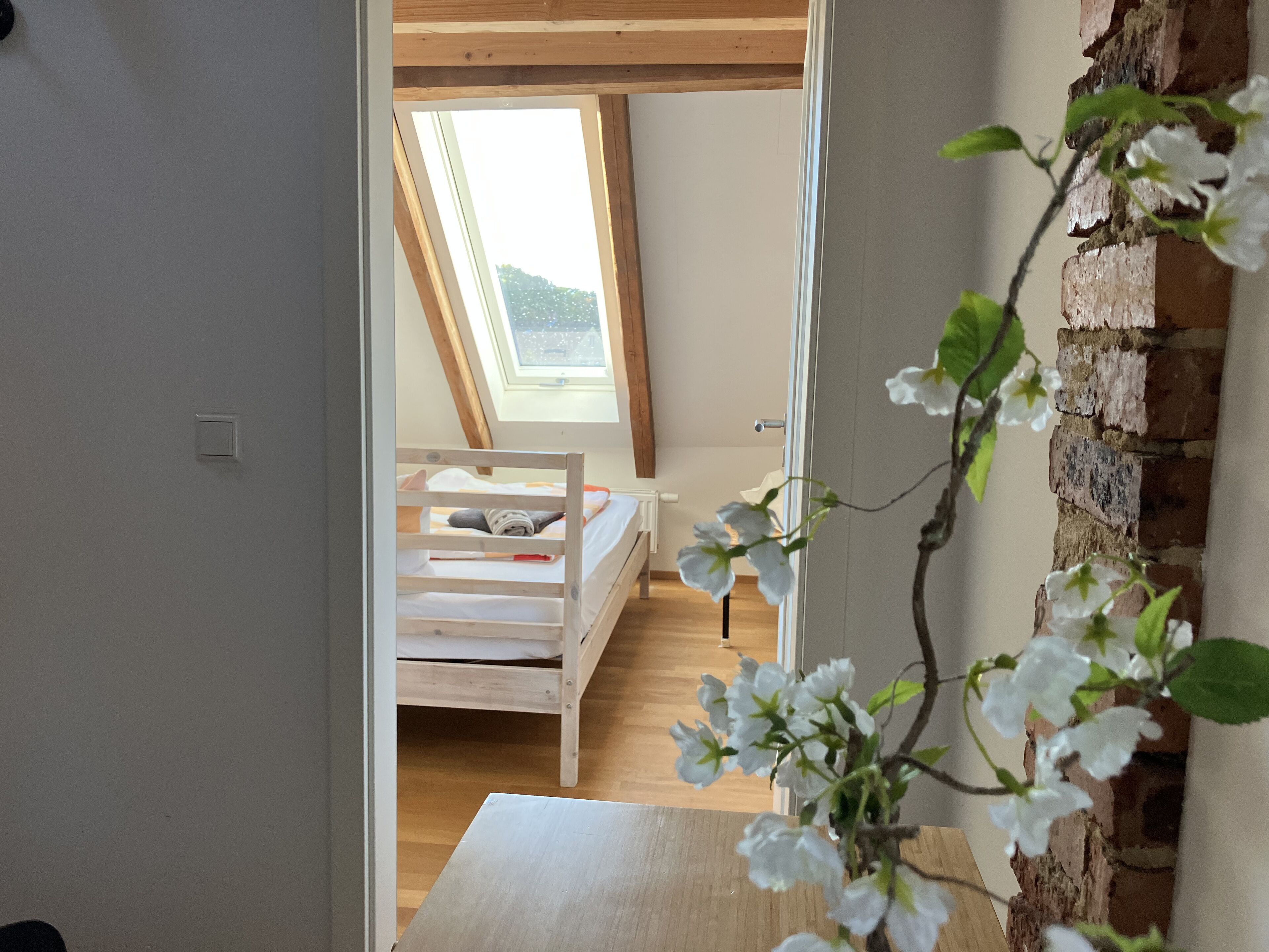 Ein Schlafzimmer mit Schrägdecke, einem Holzbett und einem Dachfenster.