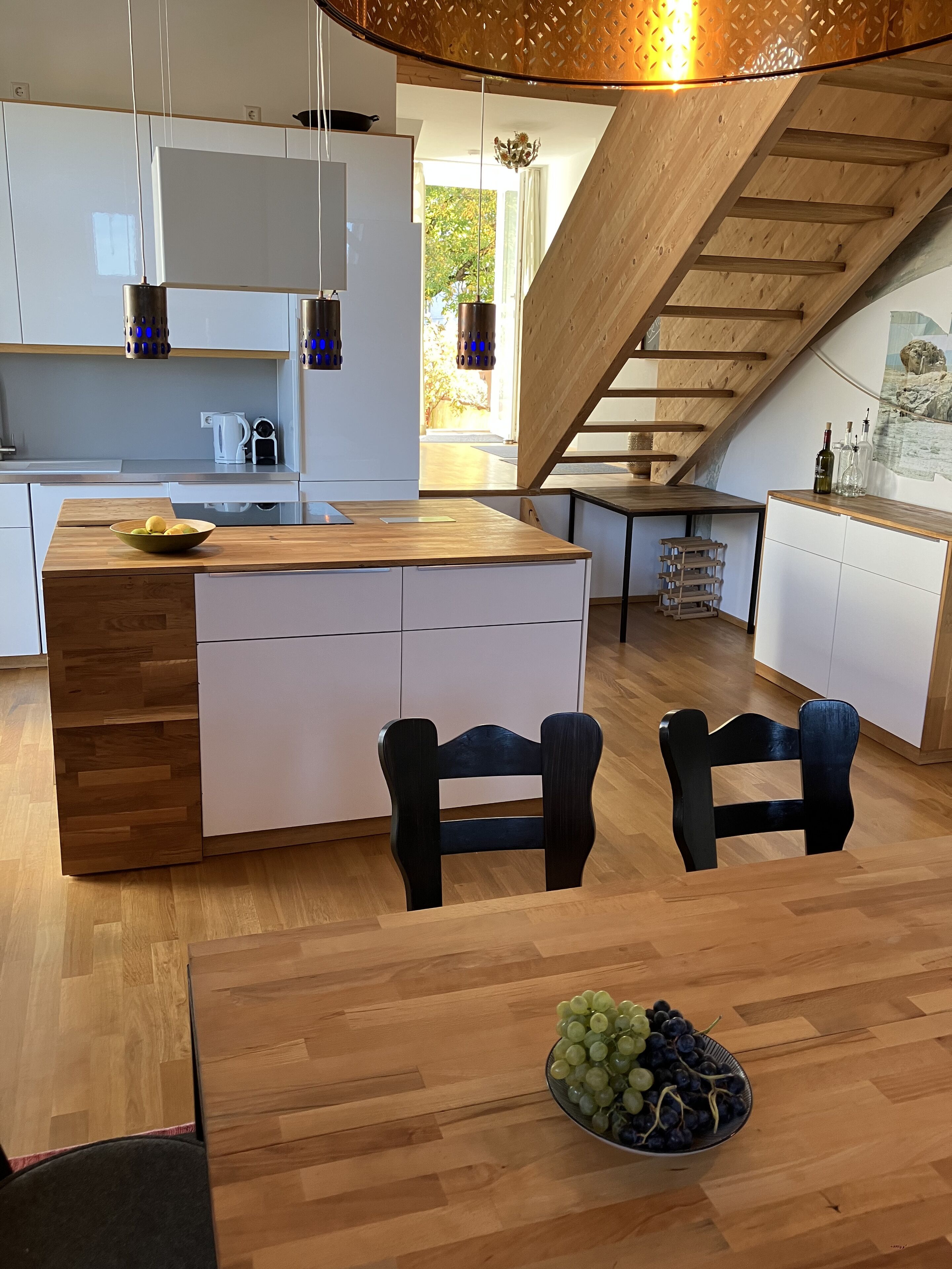 Eine moderne Küche mit einer Holzinsel, weißen Schränken und einem Essbereich mit Holztisch und Stühlen.