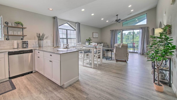 A spacious kitchen with white cabinets, a dishwasher, and a dining area with a table and chairs. - Greens View - Golf, 1 Block from the Strip! (Branson)