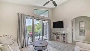 A spacious living room with a ceiling fan, a round coffee table, and a flat-screen TV mounted on the wall. - Greens View - Golf, 1 Block from the Strip! (Branson)