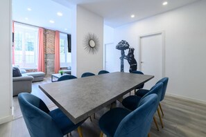 A modern dining area with a rectangular table and blue upholstered chairs. - 5BR 3BTH · City Center · Quiet · Temporary Stay (Madrid)