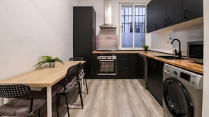 Cocina compacta con comedor, horno empotrado, microondas y lavadora.