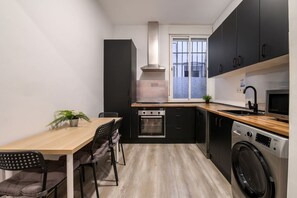 Een kleine keuken met een eethoek, een inbouwoven, een magnetron en een wasmachine.