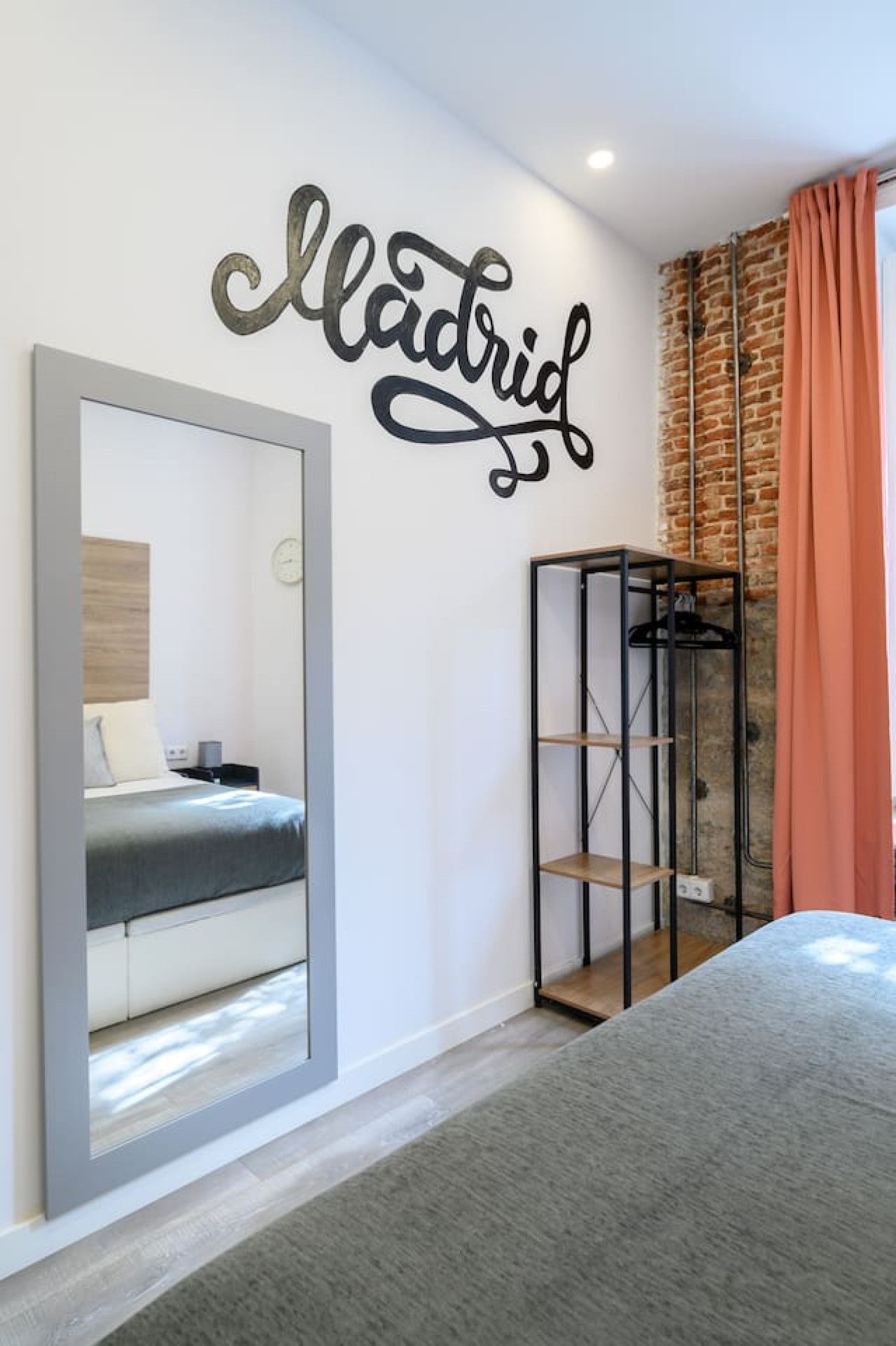 Une chambre moderne avec un lit, une armoire, un miroir et un mur sur lequel est écrit le mot « Madrid ».
