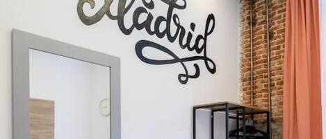 Une chambre moderne avec un lit, une armoire, un miroir et un mur sur lequel est écrit le mot « Madrid ».