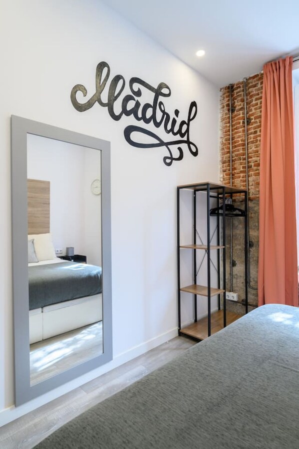 Un dormitorio moderno con una cama, un armario, un espejo y una pared con la palabra 'Madrid' escrita.