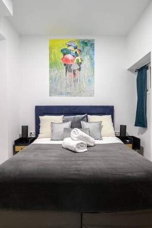 A modern bedroom with a large bed, a headboard, and a painting above it. - 5BR 3BTH · City Center · Quiet · Temporary Stay (Madrid)