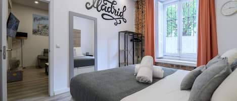 A modern bedroom with a bed, a mirror, a window with curtains, and a wall with the word "Madrid" written on it.