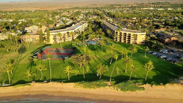 An aerial view of a resort with multiple buildings, a tennis court, and a beachfront. - Ocean view on the 4th floor A-411 (Kihei)