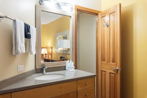 A bathroom with a sink, mirror, towel rack, and wooden door.