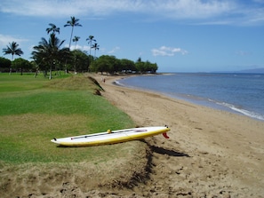 Uma praia com uma prancha de surf na areia, perto da beira da água.