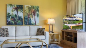 A living room with a sofa, a TV, and two paintings on the wall. - Maui Sunset Vacation Rentals- B318 (Kihei)