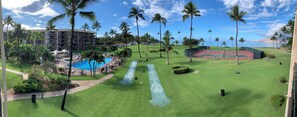 A resort with a swimming pool, tennis courts, and palm trees.