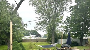 A backyard with a hot tub, outdoor furniture, and a patio area. - Cheerful, Newly Renovated Cottage close to Newport w/ hot tub! (MIddletown)