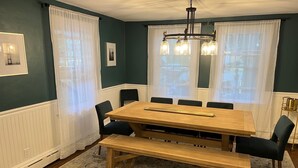 A dining room with a wooden table, black chairs, and a bench. - Cheerful, Newly Renovated Cottage close to Newport w/ hot tub! (MIddletown)