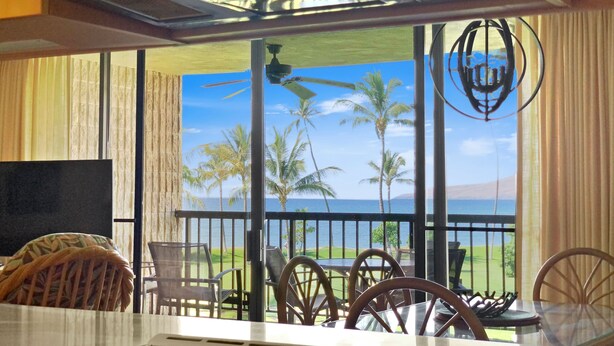 A kitchen with a view of a tropical landscape, including palm trees and a body of water. - Oceanfront condo on wing of complex near beach, pool - Perfect for Sunsets (Kihei)