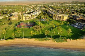 An aerial view of a resort with multiple buildings, a tennis court, and a beachfront. - Maui Sunset Vacation Rentals B419 (Kihei)