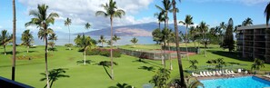 Un parcours de golf doté d’une piscine, de palmiers et offrant une vue sur une montagne et l’océan.