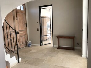 A hallway with a wooden door, a black-framed glass door, a small wooden table, and a bag of cat litter. - La Soleillade Aixoise (Aix-en-Provence)