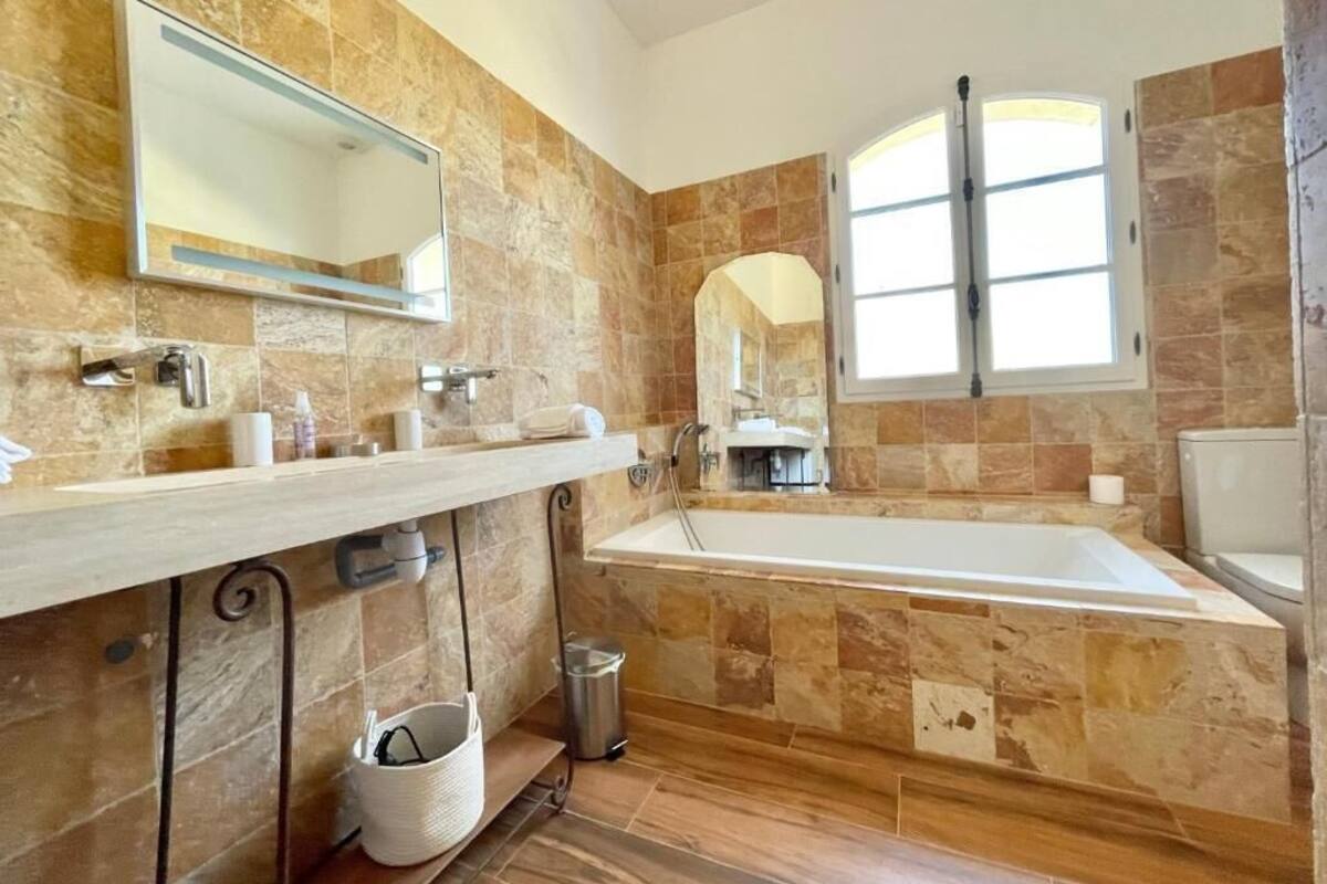 A bathroom with a large bathtub, a mirror, and a window.