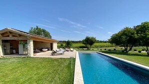 A swimming pool with a patio area, a covered structure, and a grassy landscape. - La Soleillade Aixoise (Aix-en-Provence)