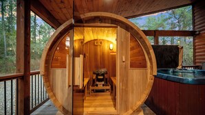 Pyöreän muotoinen puinen sauna, jossa on penkki ja poreallas.