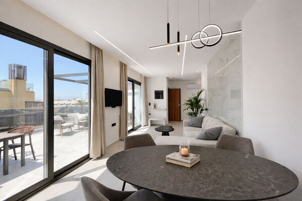 A modern living room with a round table, a sofa, and a TV mounted on the wall.
