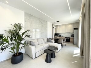 A modern living room with a sectional sofa, a coffee table, and a potted plant.