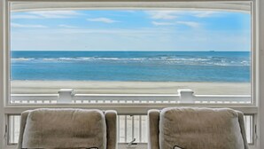 Vue depuis une chambre dotée d’une grande fenêtre donnant sur une plage.
