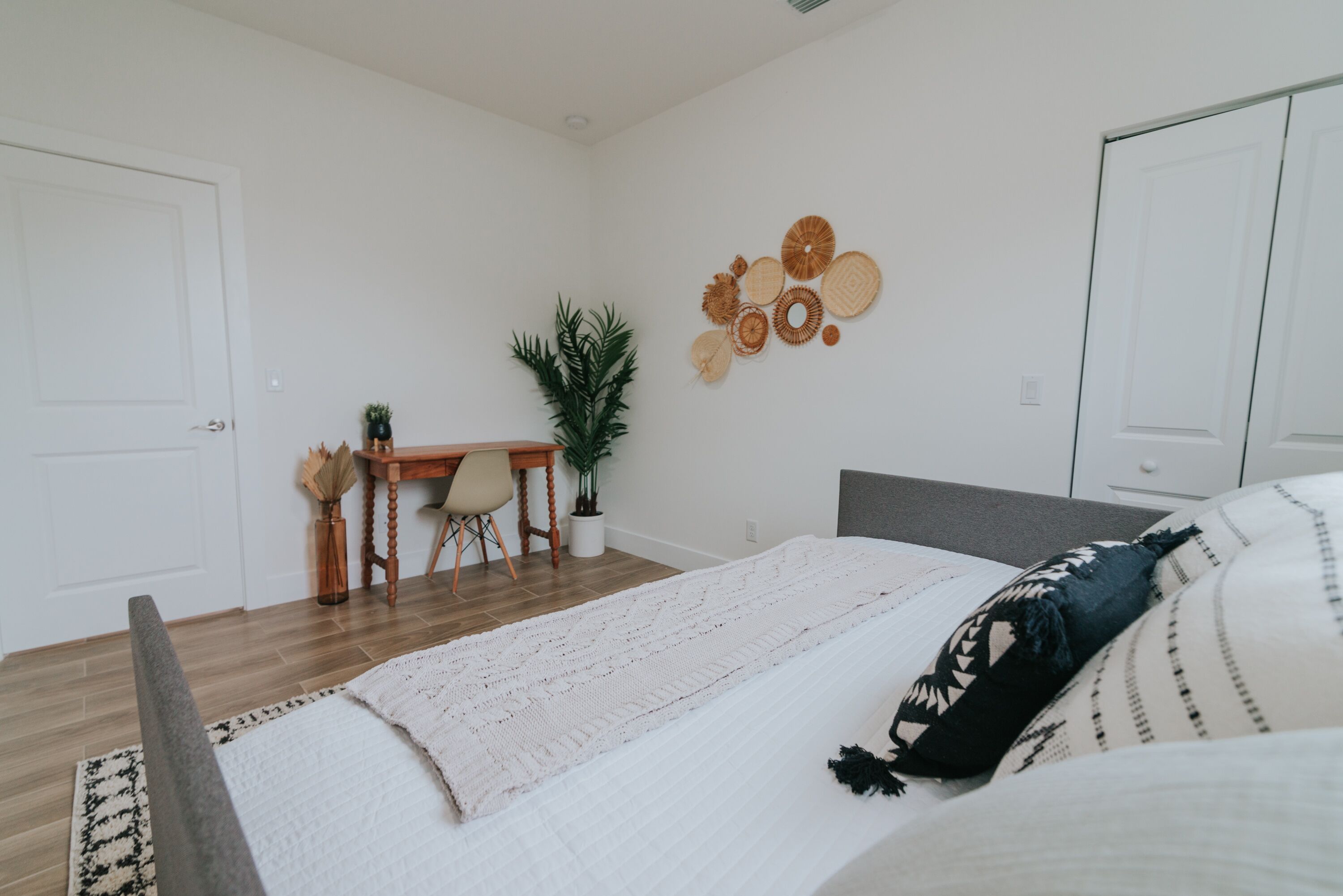 Ein Schlafzimmer mit Bett, Schreibtisch und einer Topfpflanze.