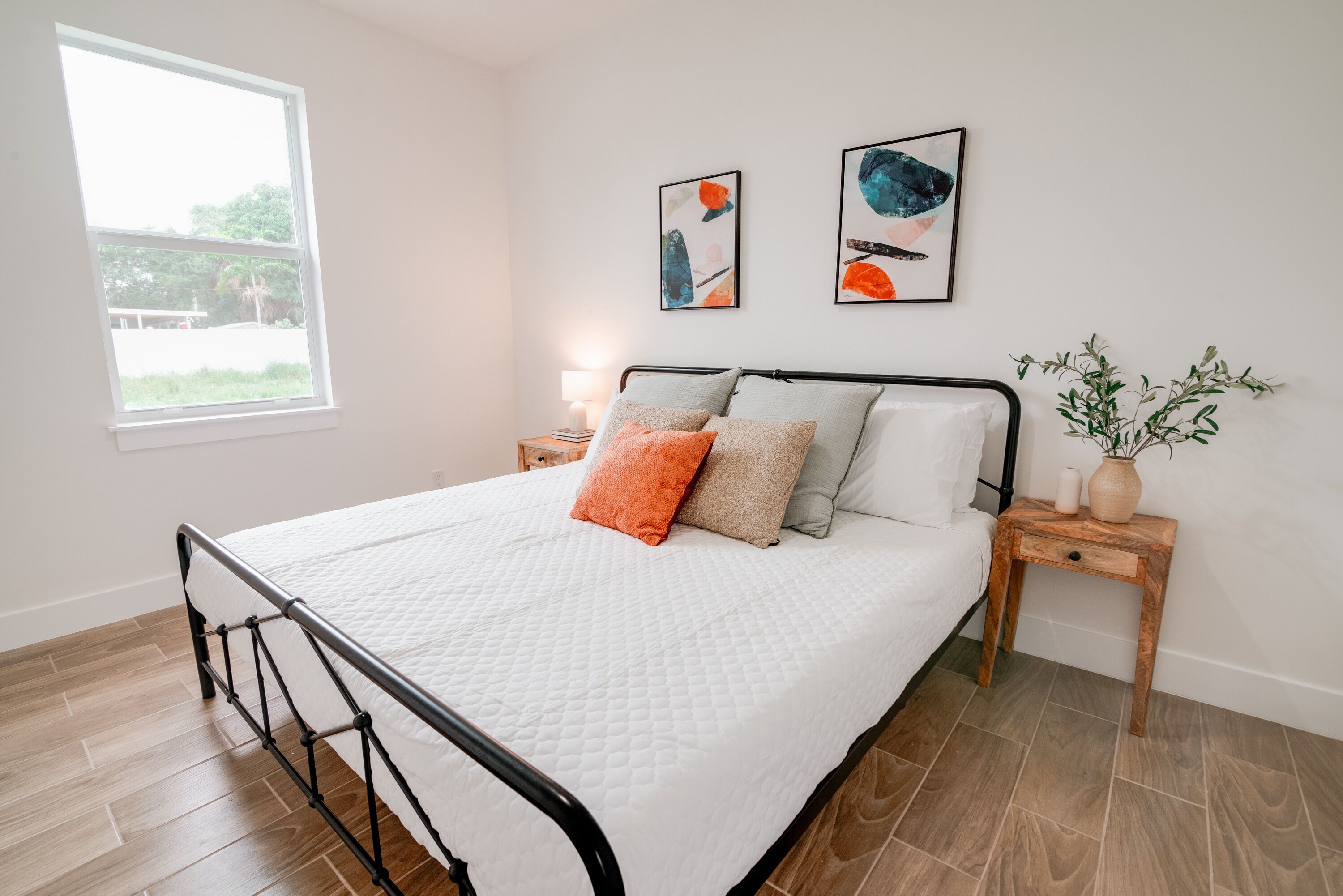 A neatly made bed with a white quilt, two pillows, and a small bedside table with a lamp.