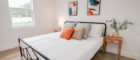 A neatly made bed with a white quilt, two pillows, and a small bedside table with a lamp.