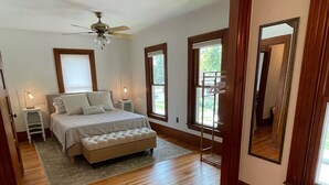 Une chambre à coucher avec un lit, un ventilateur de plafond et de grandes fenêtres.
