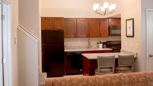 A modern kitchen with wooden cabinets, a stainless steel refrigerator, and a granite countertop.