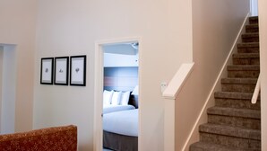 A modern interior with a chandelier, a staircase, and a bed in the background.