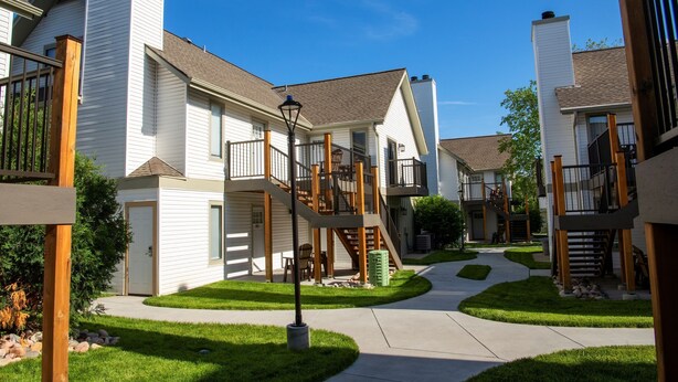 A residential area with modern houses featuring balconies, a central walkway, and a well-maintained lawn.