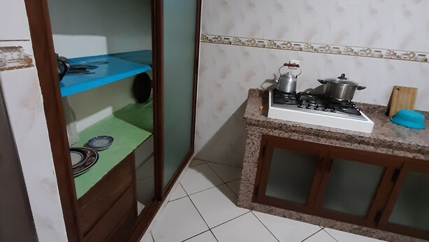 A compact kitchen with a gas stove, a small countertop, and a cabinet with glass doors.