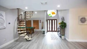 Ein modernes Interieur mit einer Holztreppe, einem Essbereich und einem Flur, der zu einer Tür führt.