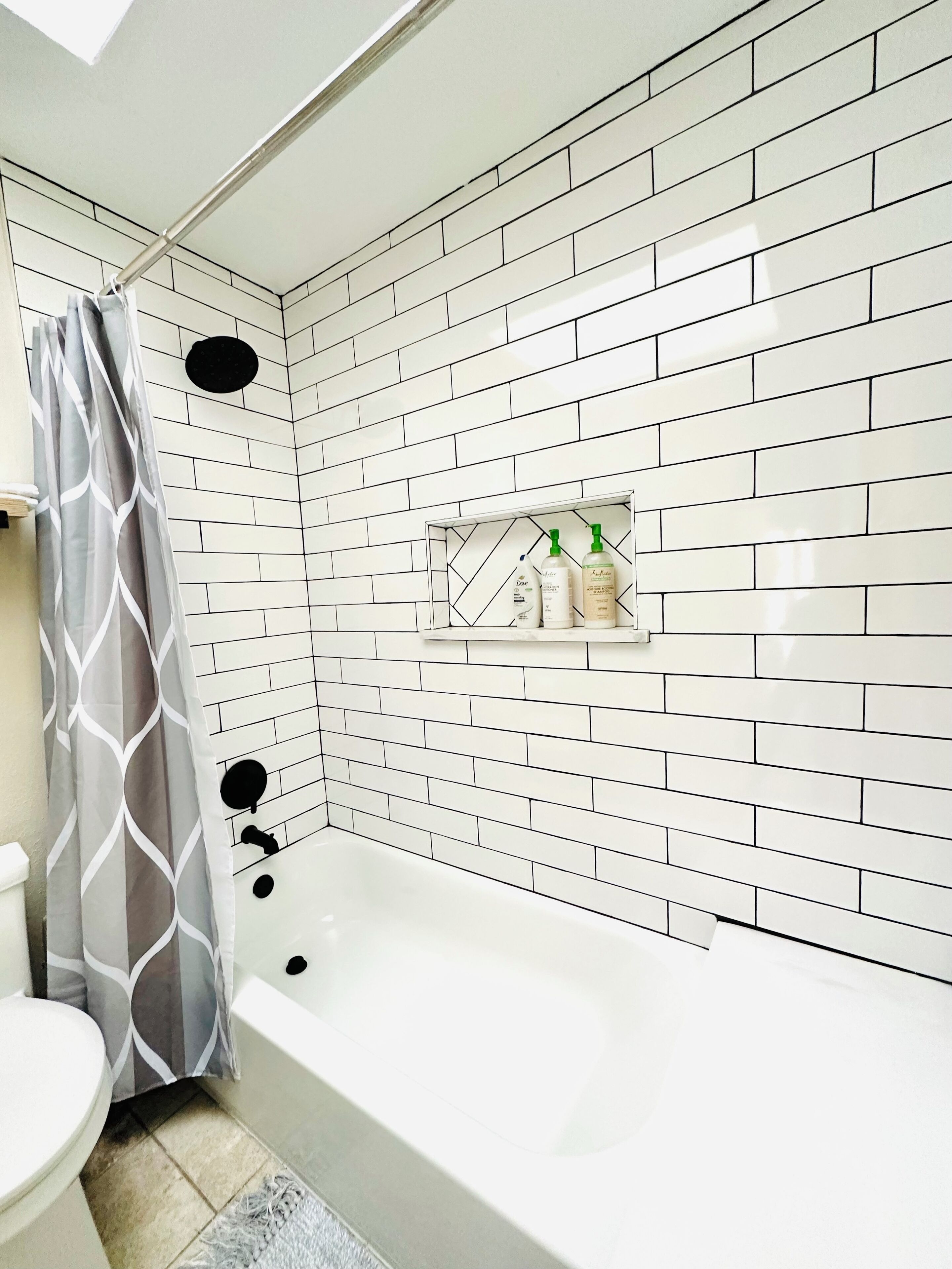Een badkamer met een witte betegelde douchewand, een bad en een douchegordijn.