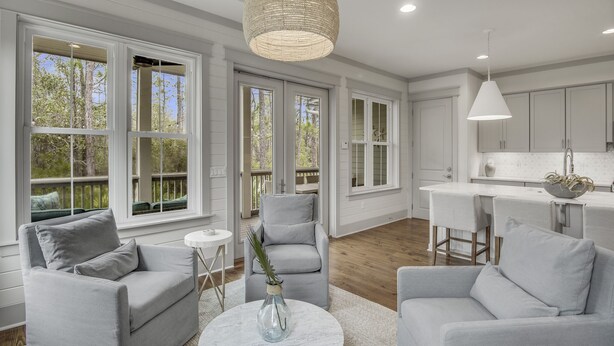 A spacious living room with a grey sofa set, a coffee table, and a large window with a view of trees. - Beargrass. 4 Bedroom Newly Updated with 6-Seater Golf Cart & Bikes! (Santa Rosa Beach)