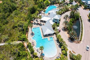 An aerial view of a resort with multiple swimming pools, a large central pool, and a guest lounge area with sun loungers.