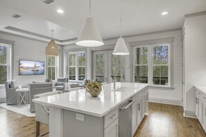 A spacious kitchen with a large island, white cabinetry, and pendant lighting.