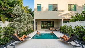 A modern outdoor pool area with lounge chairs and a building in the background.