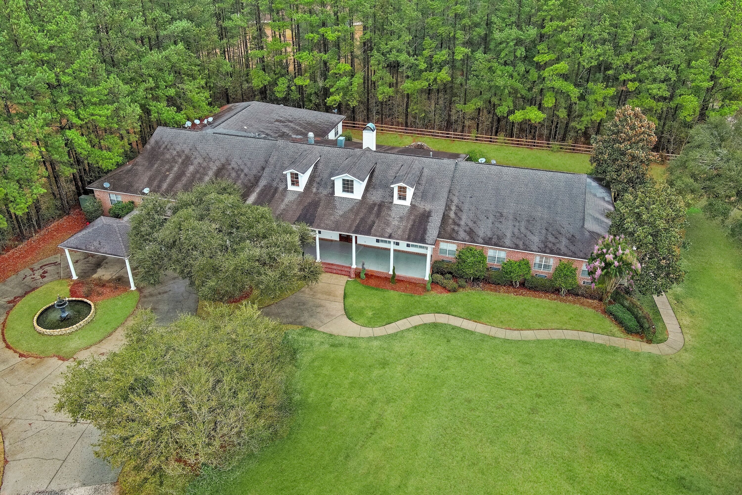 A large house with a sloped roof, multiple chimneys, and a well-maintained lawn.