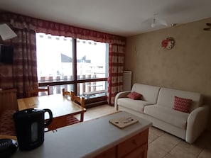 Ein Wohnzimmer mit einem weißen Sofa, einem Holzesstisch und einer Kaffeemaschine.