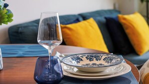 Ein Essbereich mit einem Tisch für zwei Personen, bestehend aus einem Glas, einem blauen Teller und einem weißen Teller mit blauem Blumenmuster.